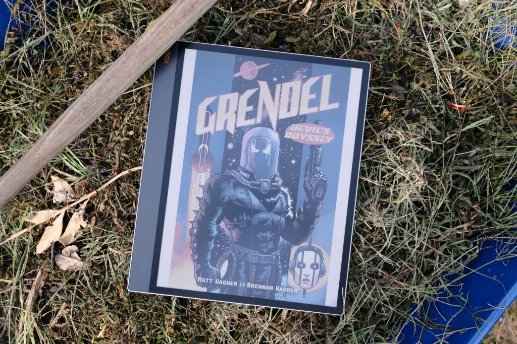 Boox Tab X C with Grendel comic on screen while laying in grass in wheelbarrow