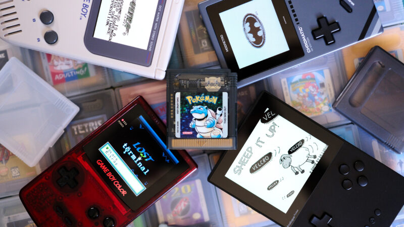 Game Boy cart laying on top of handhelds and games