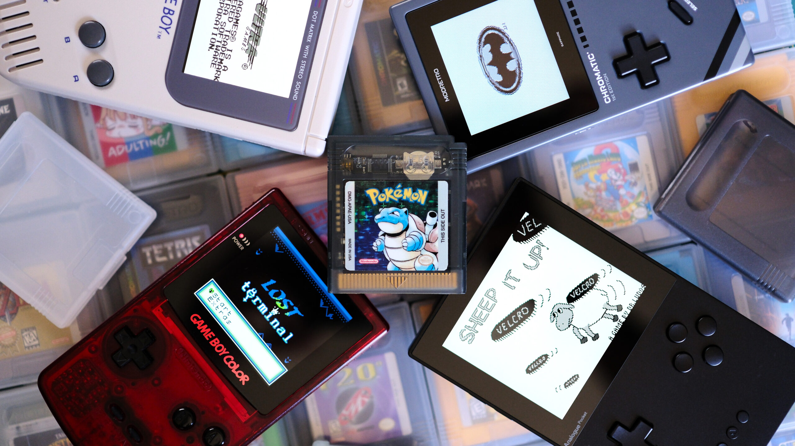 Game Boy cart laying on top of handhelds and games