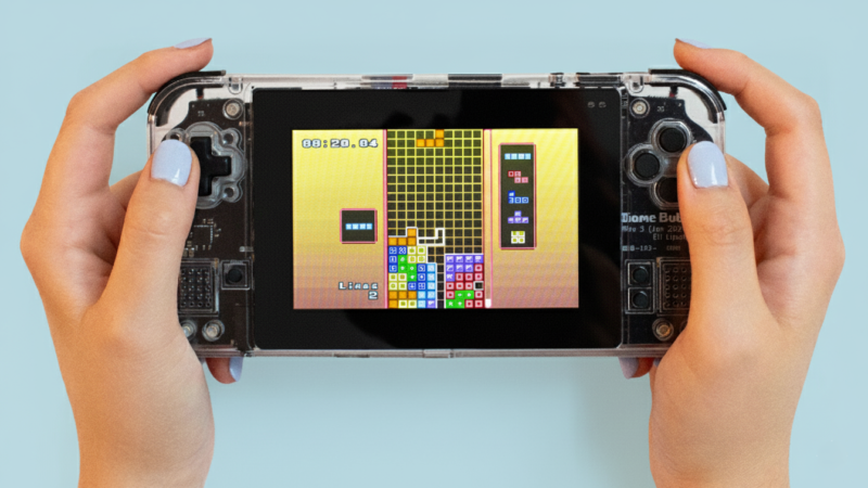 Game Bub held in hand with color background added with Gemini