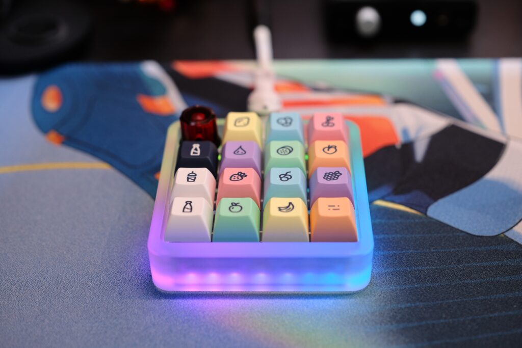 Vault 16 macropad laying on deskmat with LEDs on