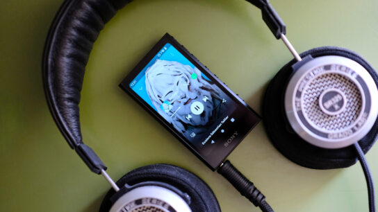 Spotify playing on Sony DAP with headphones plugged in laying on green table