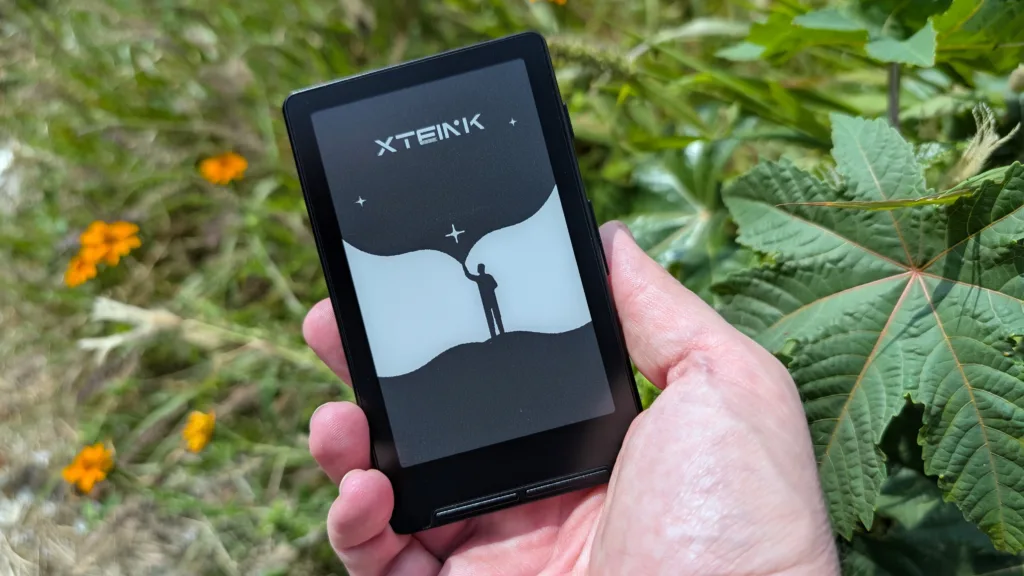 Xteink X4 in hand in front of lush vegetation