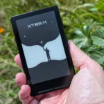 Xteink X4 in hand in front of lush vegetation