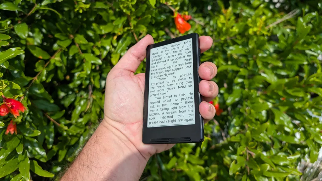 Xteink X4 in hand in front of green vegetation