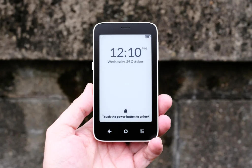 Mudita Kompakt held in hand in front of brick wall