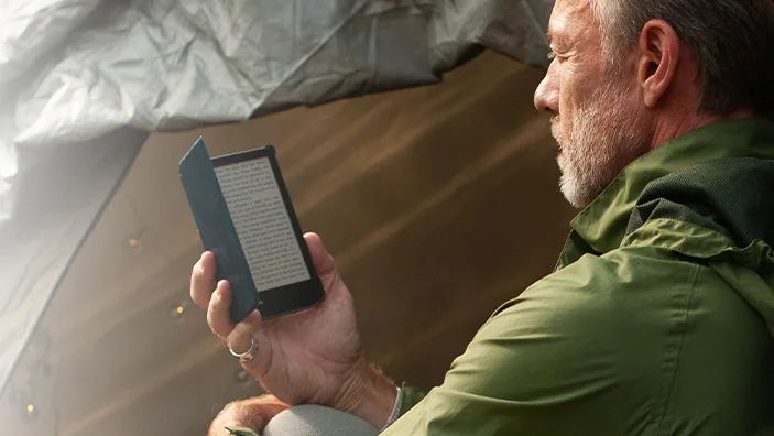 Man outdoors reading a black PocketBook Verse outside of a tent