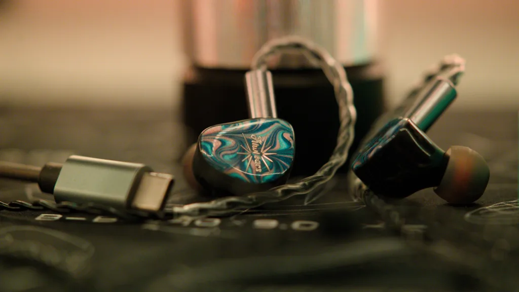 Cadenza IEM with a USB dongle DAC on a printed deskmat in dim lighting