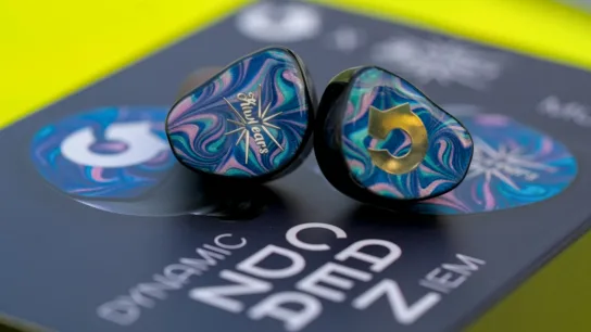 Two shimmering IEM earbuds placed on their product packaging