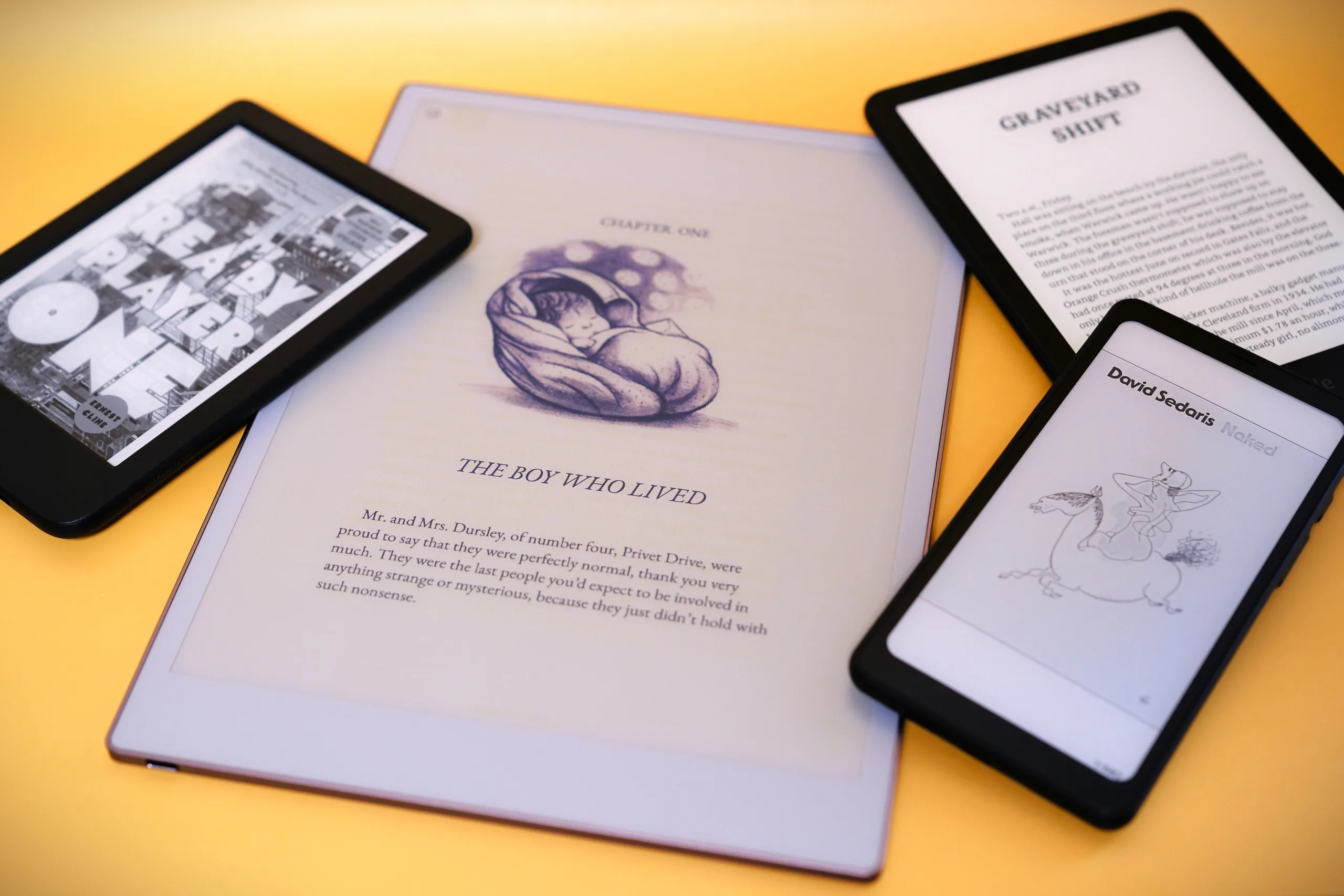 Small pile of e-readers from different brands on yellow backgroun