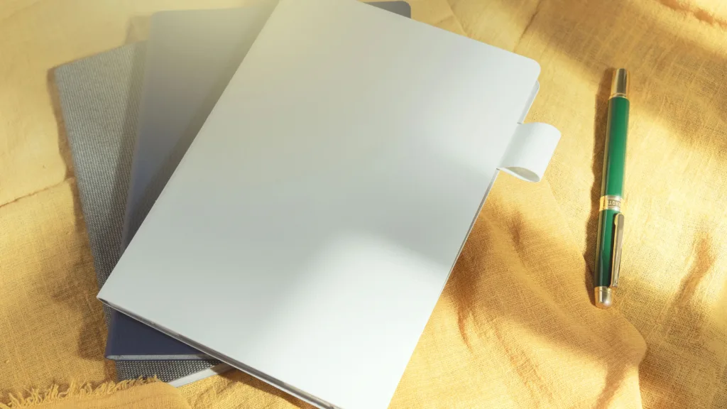 Supernote Nomad e-reader on top of notebooks, next to pen, on yellow cloth