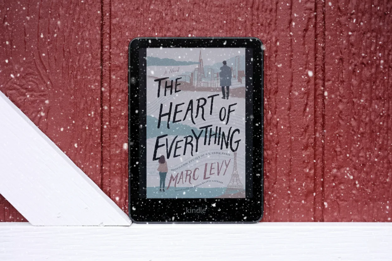 Kindle sitting against red barn door showing book on screen