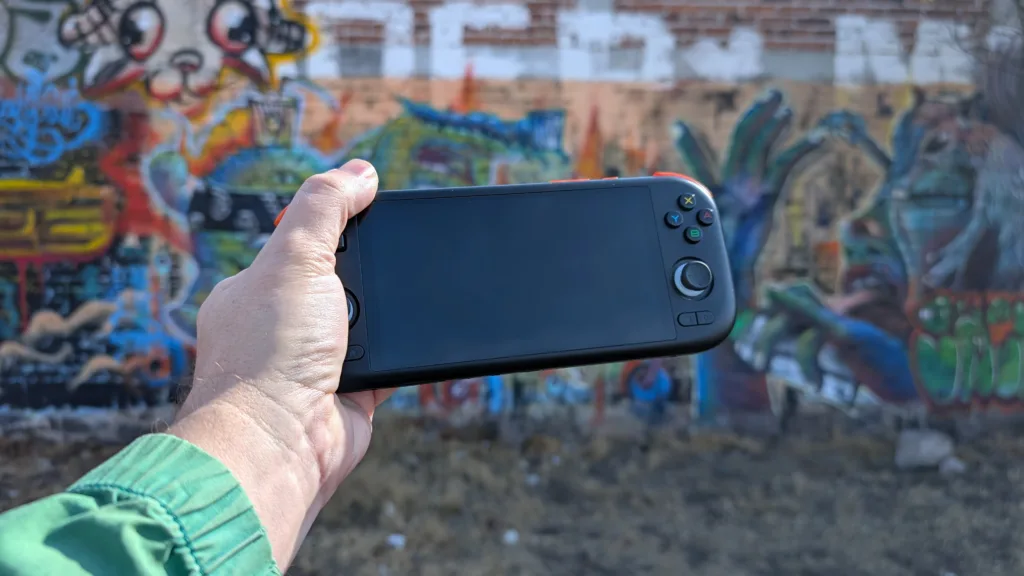 Black Mangmi Air X in hand in front of graffiti wall