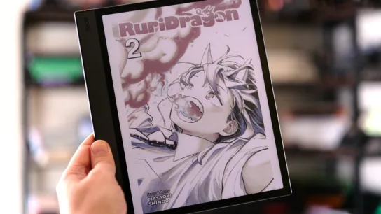 Boox Air5 C held in hand in front of shelves