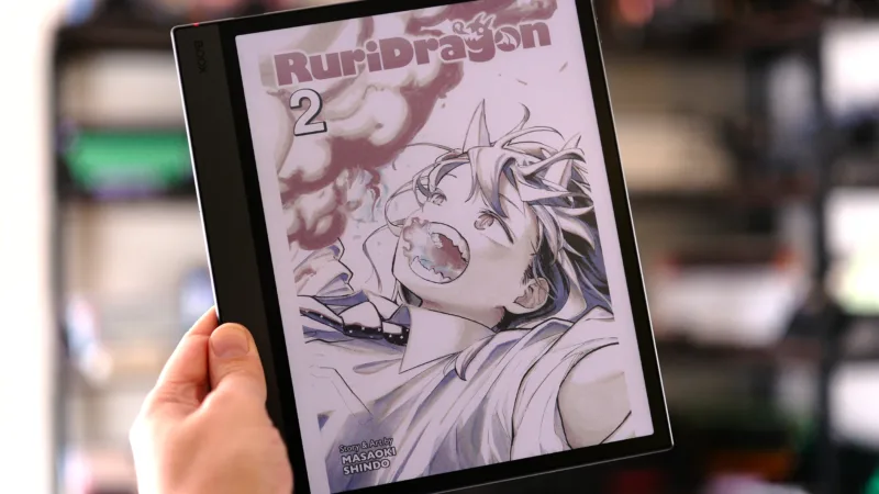 Boox Air5 C held in hand in front of shelves