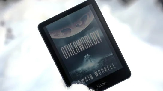 Kindle Colorsoft propped up in snow with book on screen