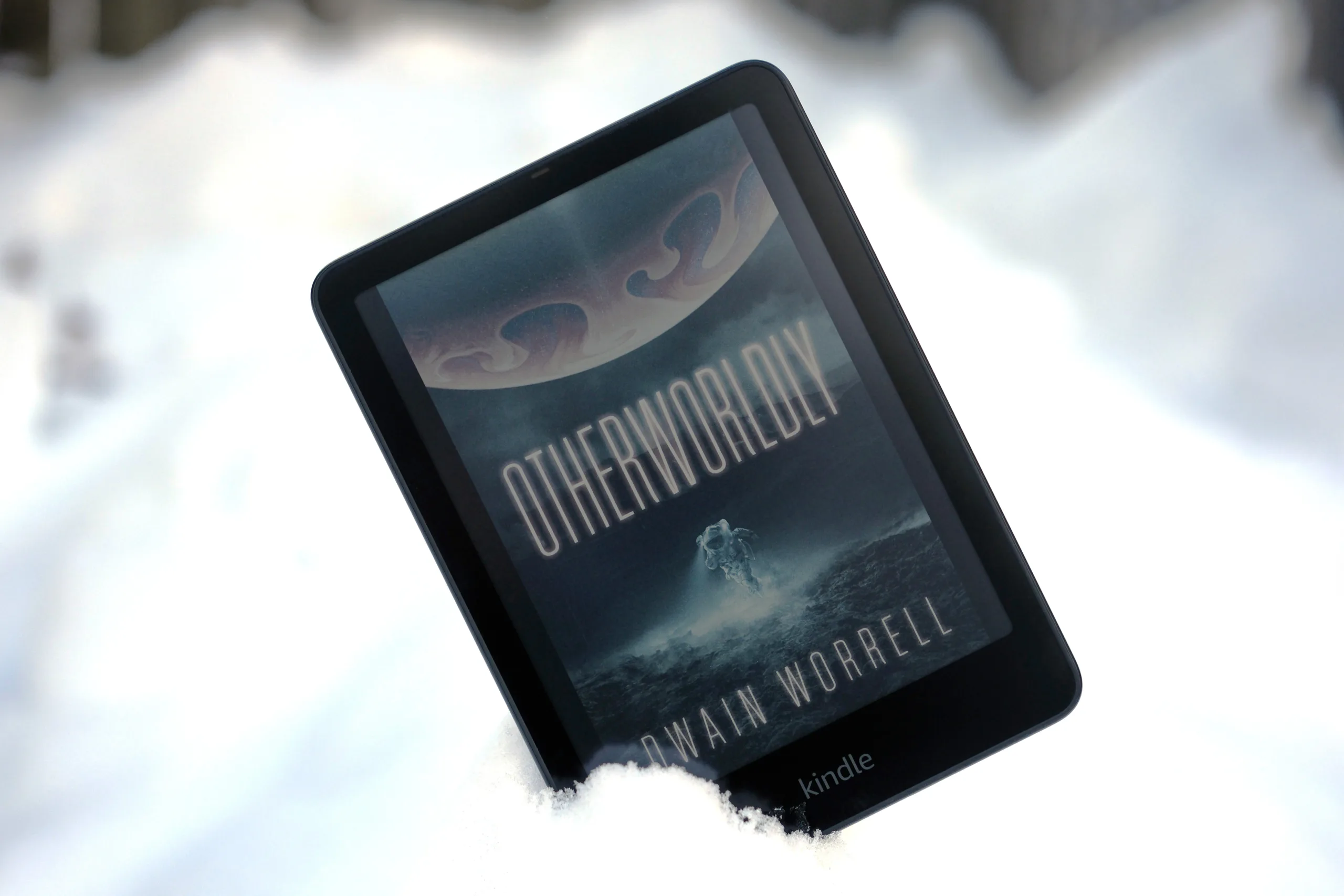 Kindle Colorsoft propped up in snow with book on screen