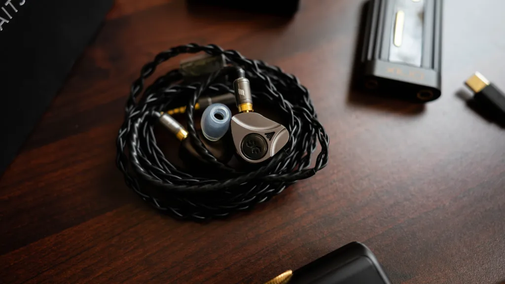 Elysian Apostle 2026 with Spinfit W1 eartips rolled beside the Shanling Onix Xi2 source