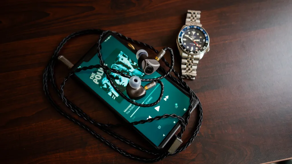 Elyisan Apostle 2026 plugged into the Shanling M9 Plus DAP beside a Seiko 5 GMT watch