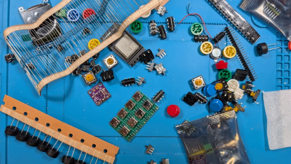 Pile of components needed to assemble a Lilka on a blue soldering pad