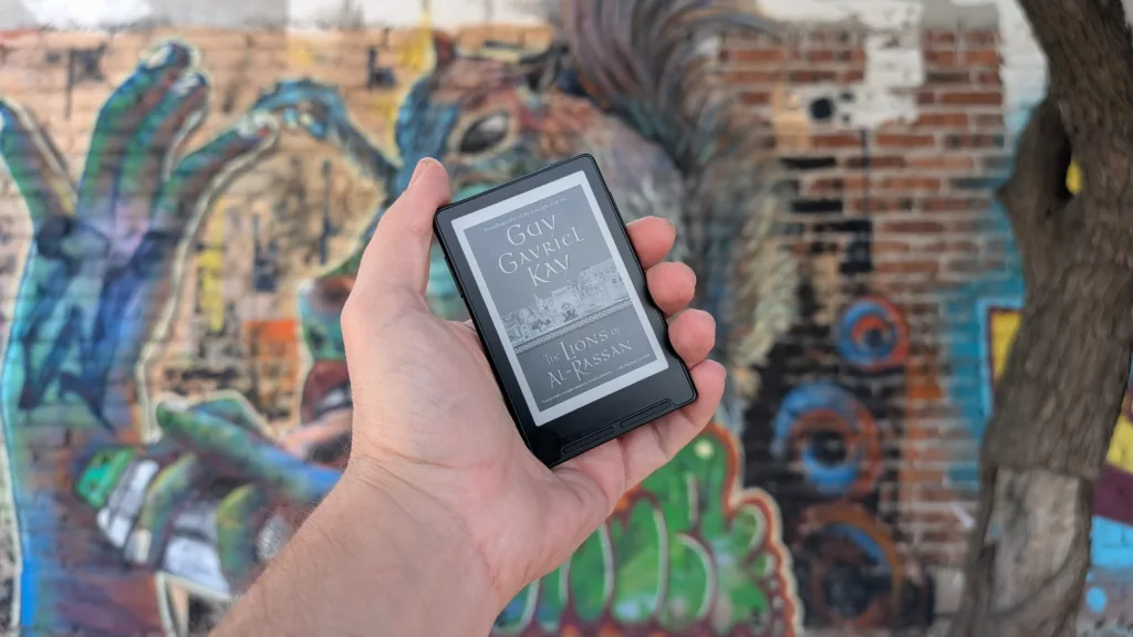 Xteink X3 book cover sleep screen in hand in front of graffiti wall