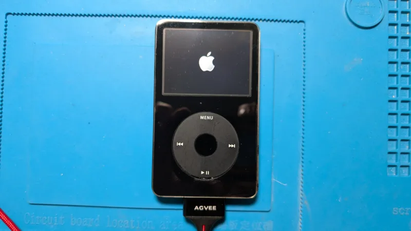 iPod on blue soldering mat with Apple icon on screen