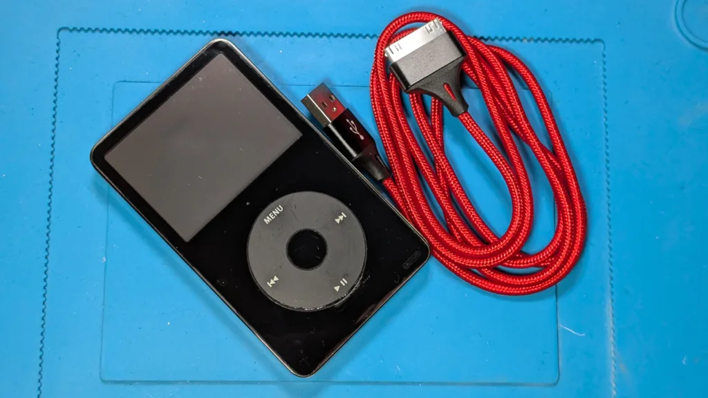 iPod with red charging cable on blue mat